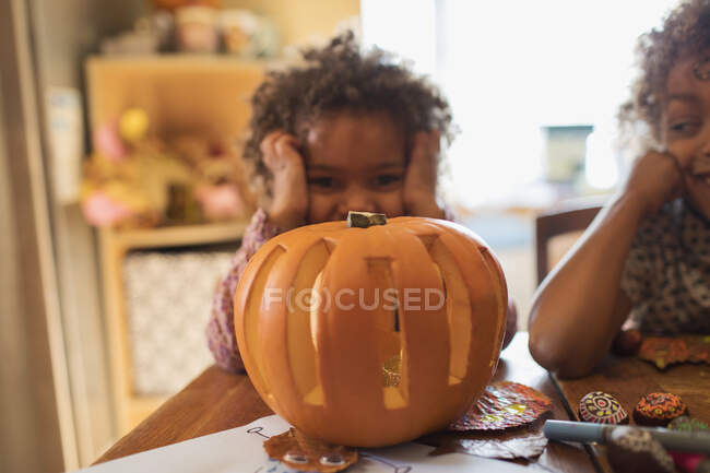 Retrato bonito menina escultura Halloween abóbora à mesa — Fotografia de Stock