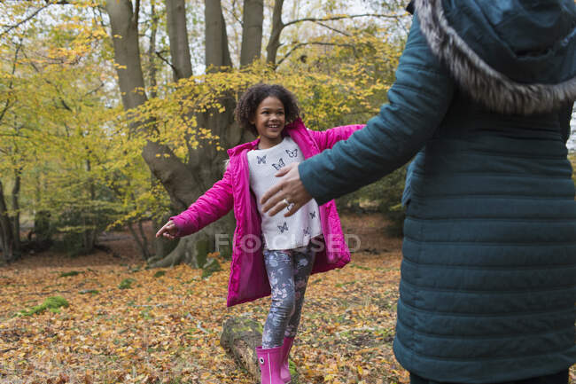 Happy mother and daughter playing on fallen log in autumn forest — Stock Photo