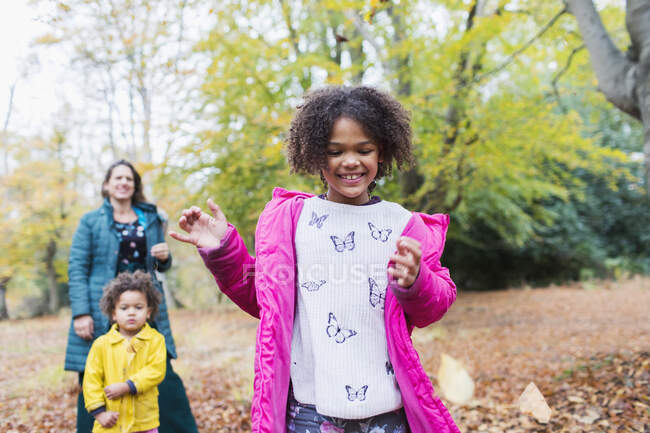 Glückliches Mädchen spielt im Herbstlaub mit Familie im Wald — Stockfoto