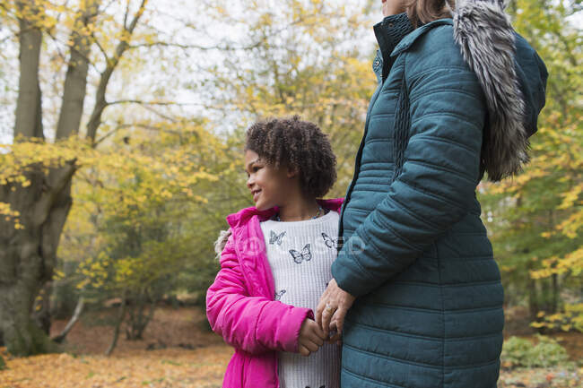 Щаслива дочка тримає руки з матір'ю в осінньому лісі — стокове фото