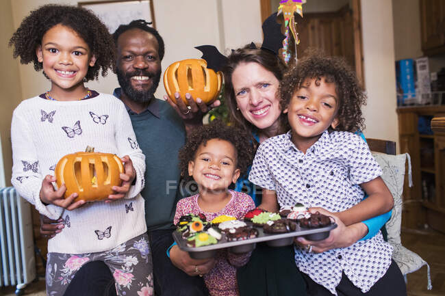Retrato familia feliz con calabazas talladas y cupcakes de Halloween - foto de stock