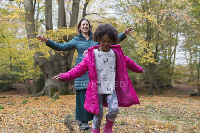 Mutter und Tochter balancieren auf umgestürzten Baumstämmen im Herbstwald — Stockfoto