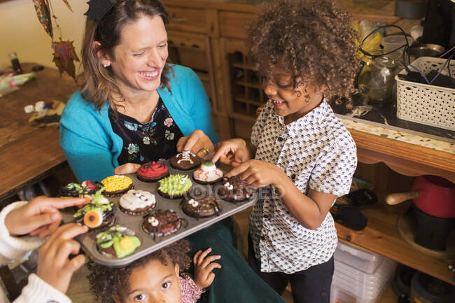Mãe feliz e crianças com cupcakes de Halloween decorados — Fotografia de Stock