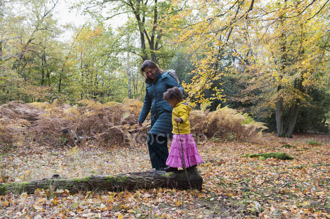 Mãe e filha andando em tronco caído em florestas de outono — Fotografia de Stock