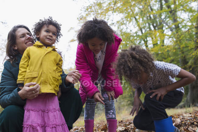 Madre felice e bambini che giocano in foglie autunnali — Foto stock