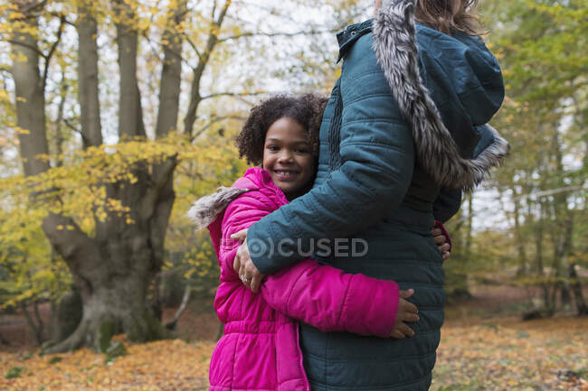 Portrait of happy girl hugging mother in autumn woods — Stock Photo