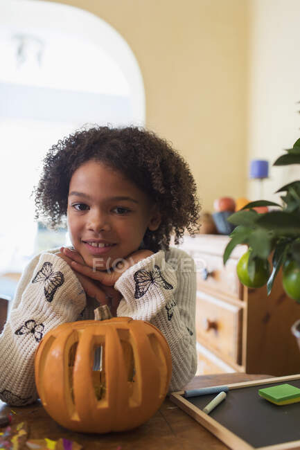 Portrait confident girl carving pumpkin at table — Stock Photo