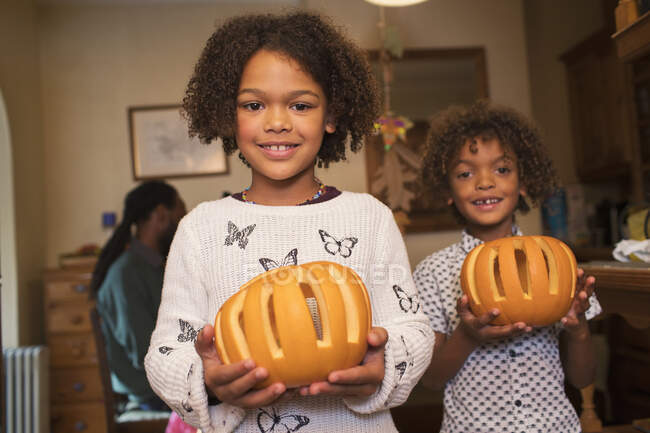 Portrait happy brother and sister holding pumpkins — Stock Photo