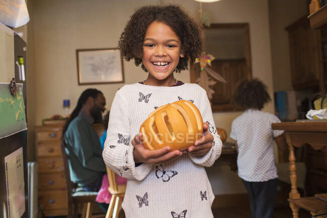 Portrait happy girl holding carved pumpkin — Stock Photo