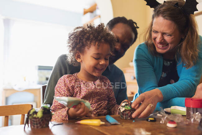 Glückliche Familie dekoriert Halloween Cupcakes — Stockfoto