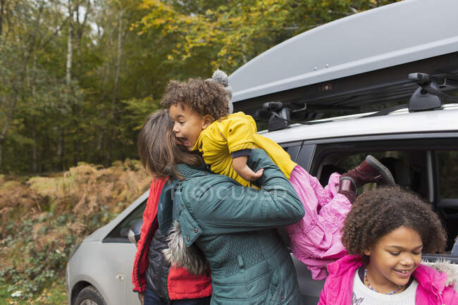 Madre sosteniendo hija fuera de coche en el estacionamiento - foto de stock