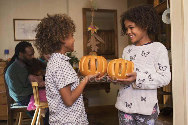 Happy brother and sister holding carved pumpkins — Stock Photo