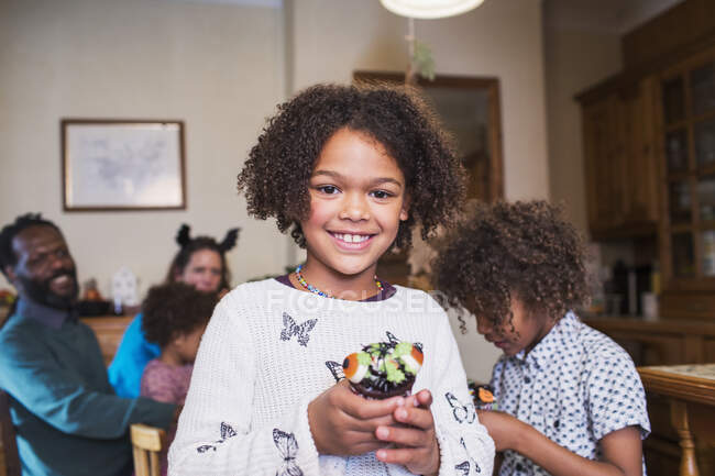 Portrait confident girl holding decorated Halloween cupcake — Stock Photo