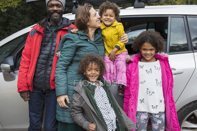 Портрет щасливої багатоетнічної сім'ї, що стоїть за автомобілем — стокове фото