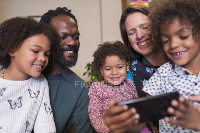 Família multiétnica feliz usando telefone inteligente — Fotografia de Stock