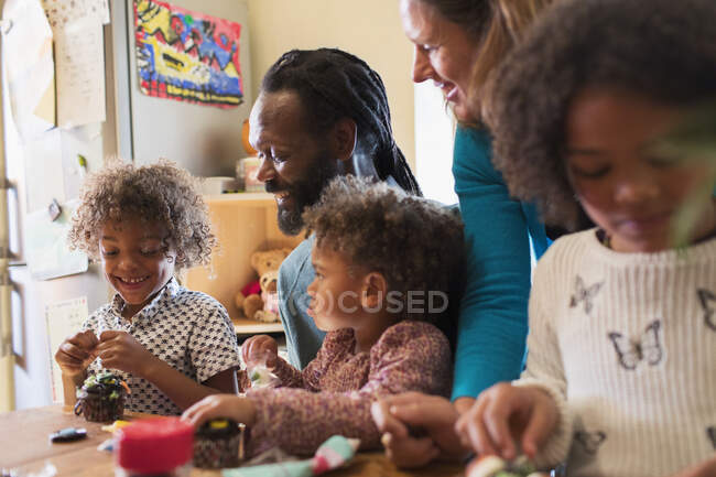 Familia multiétnica decorando cupcakes en la mesa - foto de stock