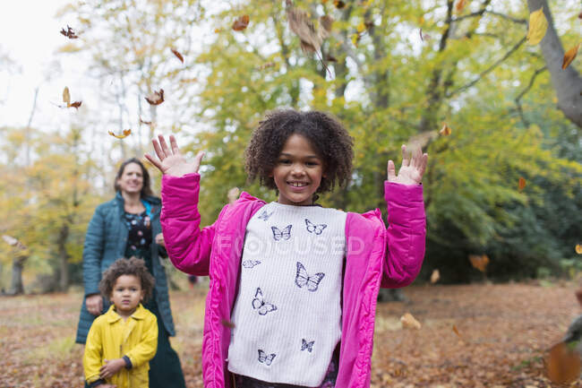 Retrato menina feliz jogando folhas de outono sobrecarga em madeiras — Fotografia de Stock