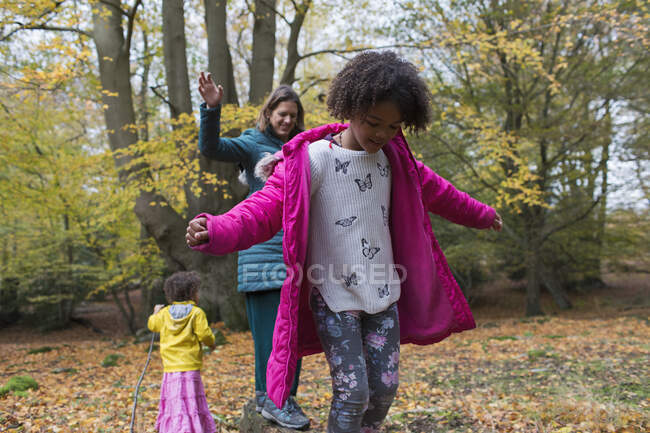 Mother and daughters balancing on fallen log in autumn woods — Stock Photo