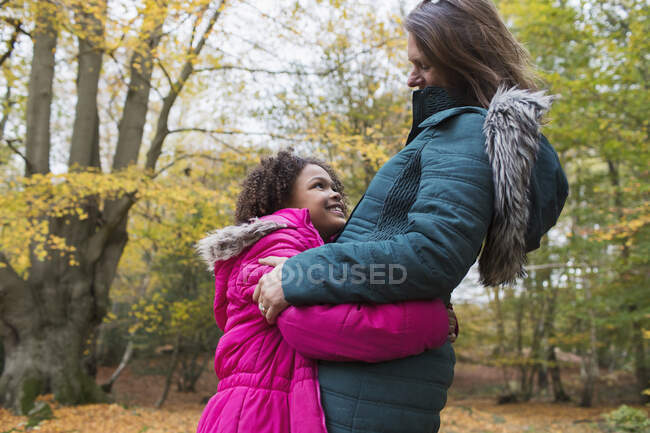Happy mother and daughter hugging in autumn woods — Stock Photo