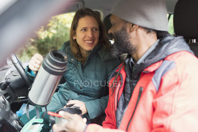 Счастливая пара пьет кофе в машине — стоковое фото