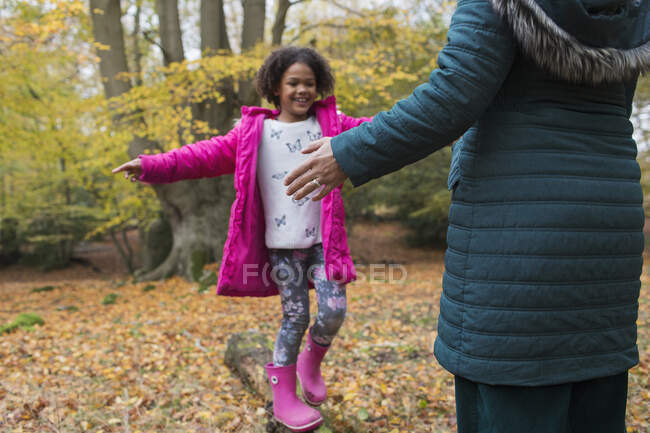 Feliz chica equilibrio en el tronco caído en los bosques de otoño - foto de stock