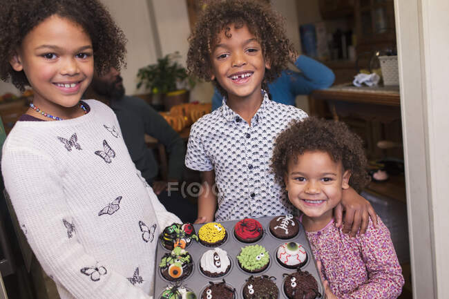 Portrait heureux frère et sœurs avec décoré cupcakes Halloween — Photo de stock