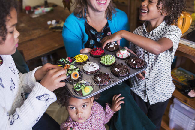 Family with decorated Halloween cupcakes — Stock Photo