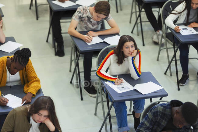 Задумчивая школьница сдает экзамен за партой в классе — стоковое фото