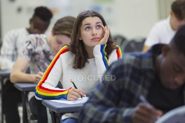 Focalizzato liceo ragazza studente prendendo esame guardando in alto — Foto stock