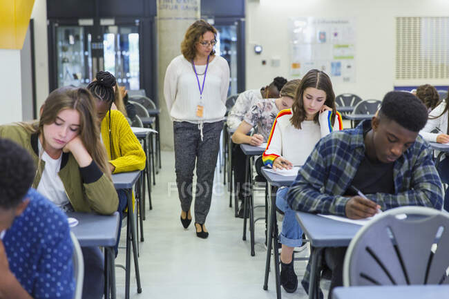 Вчитель середньої школи наглядає за студентами, які здавали іспити на парті. — стокове фото