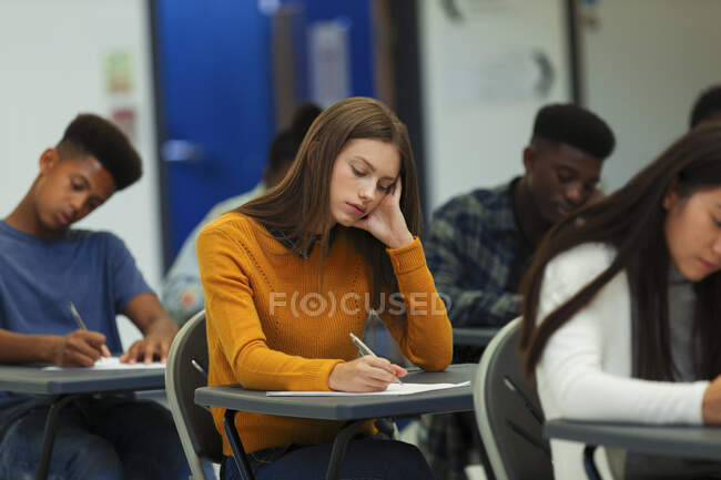 Étudiante ciblée du secondaire passant un examen au bureau en classe — Photo de stock