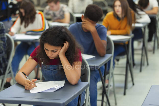 Сосредоточенные школьницы сдают экзамен за партой в классе — стоковое фото
