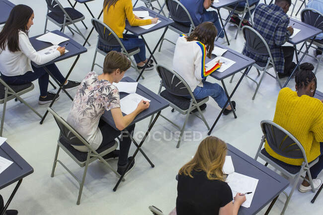 Estudantes do ensino médio fazendo exame em mesas em sala de aula — Fotografia de Stock