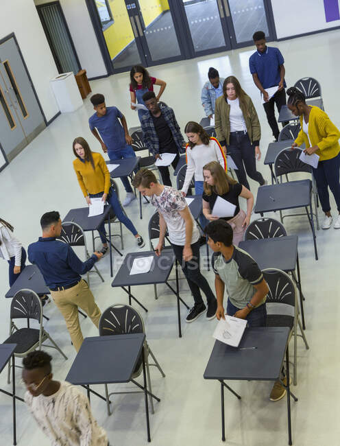 Vue d'au-dessus des élèves du secondaire qui terminent l'examen aux bureaux — Photo de stock