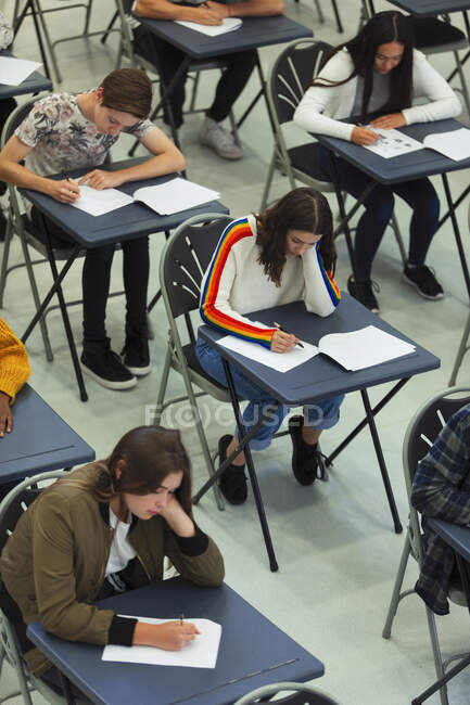 Учні старших класів складають іспит за столами — стокове фото