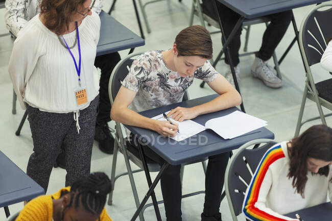 Insegnante di scuola superiore supervisionare gli studenti sostenere l'esame in classe — Foto stock