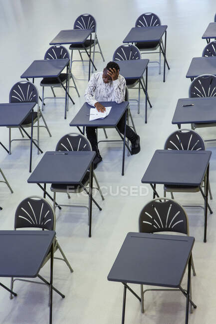 Dedicado estudante menino do ensino médio fazendo exame na mesa em sala de aula — Fotografia de Stock