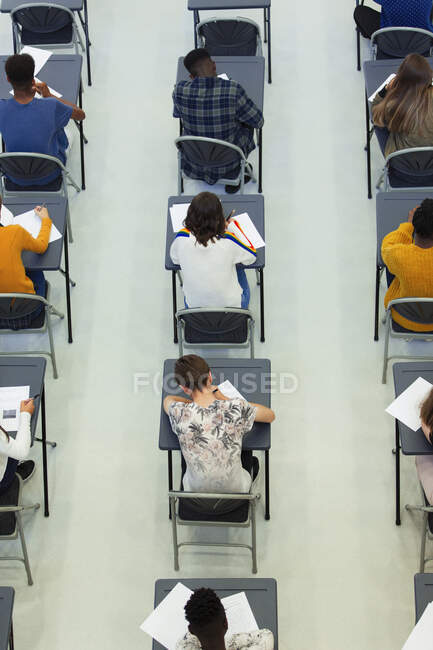 Vista desde arriba de los estudiantes de secundaria que toman examen en los escritorios en el aula - foto de stock