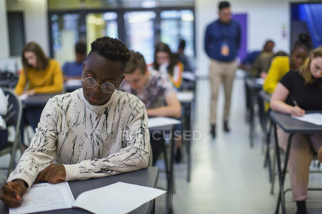 Сосредоточенный ученик старшей школы, сдающий экзамен за столом — стоковое фото