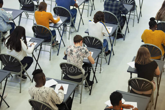 Estudiantes de secundaria tomando examen en las mesas - foto de stock