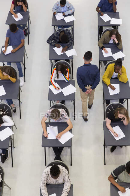 Lehrer beaufsichtigt Gymnasiasten bei Prüfungen am Schreibtisch — Stockfoto