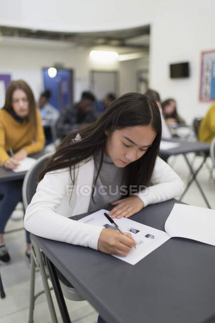 Liceo ragazza prendendo esame a scrivania in aula — Foto stock