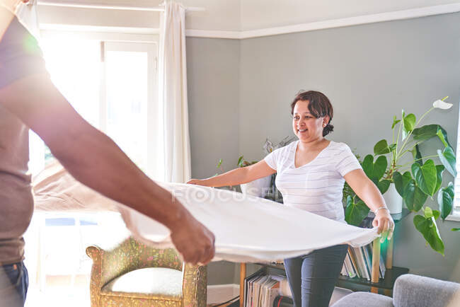 Couple folding sheet in living room — Stock Photo