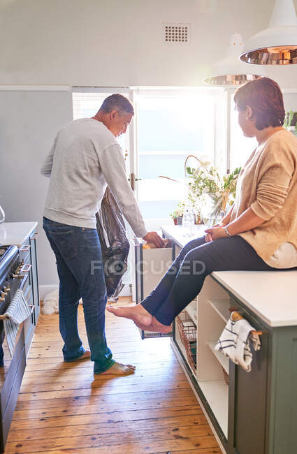 Mature couple emptying garbage in kitchen — Stock Photo