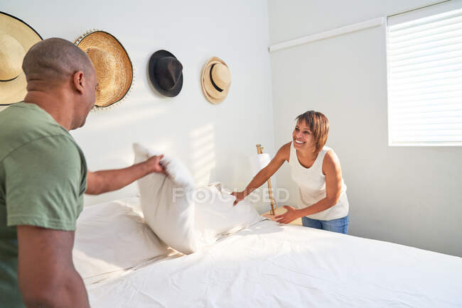 Couple making bed together in bedroom — Stock Photo