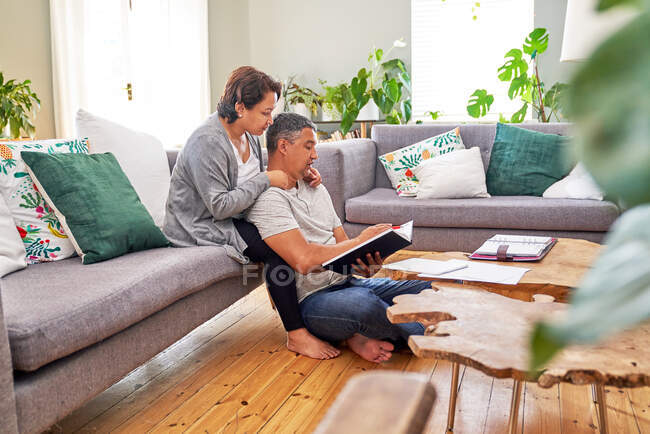 Casal maduro afetuoso lendo na sala de estar — Fotografia de Stock