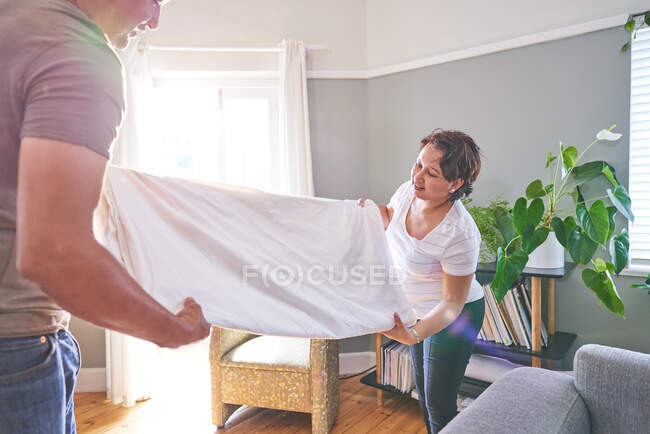 Mature couple folding sheet at home — Stock Photo