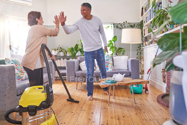 Happy mature couple cleaning house and high fiving — Stock Photo