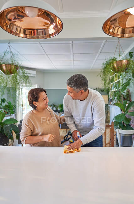 Felice coppia matura pulizia isola cucina e parlando — Foto stock