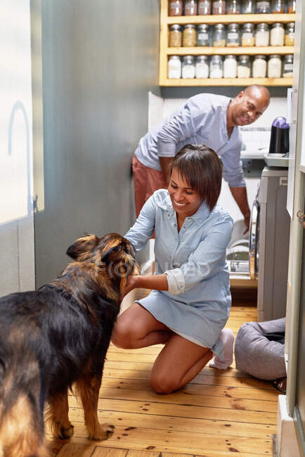 Happy couple with dog in kitchen — Stock Photo